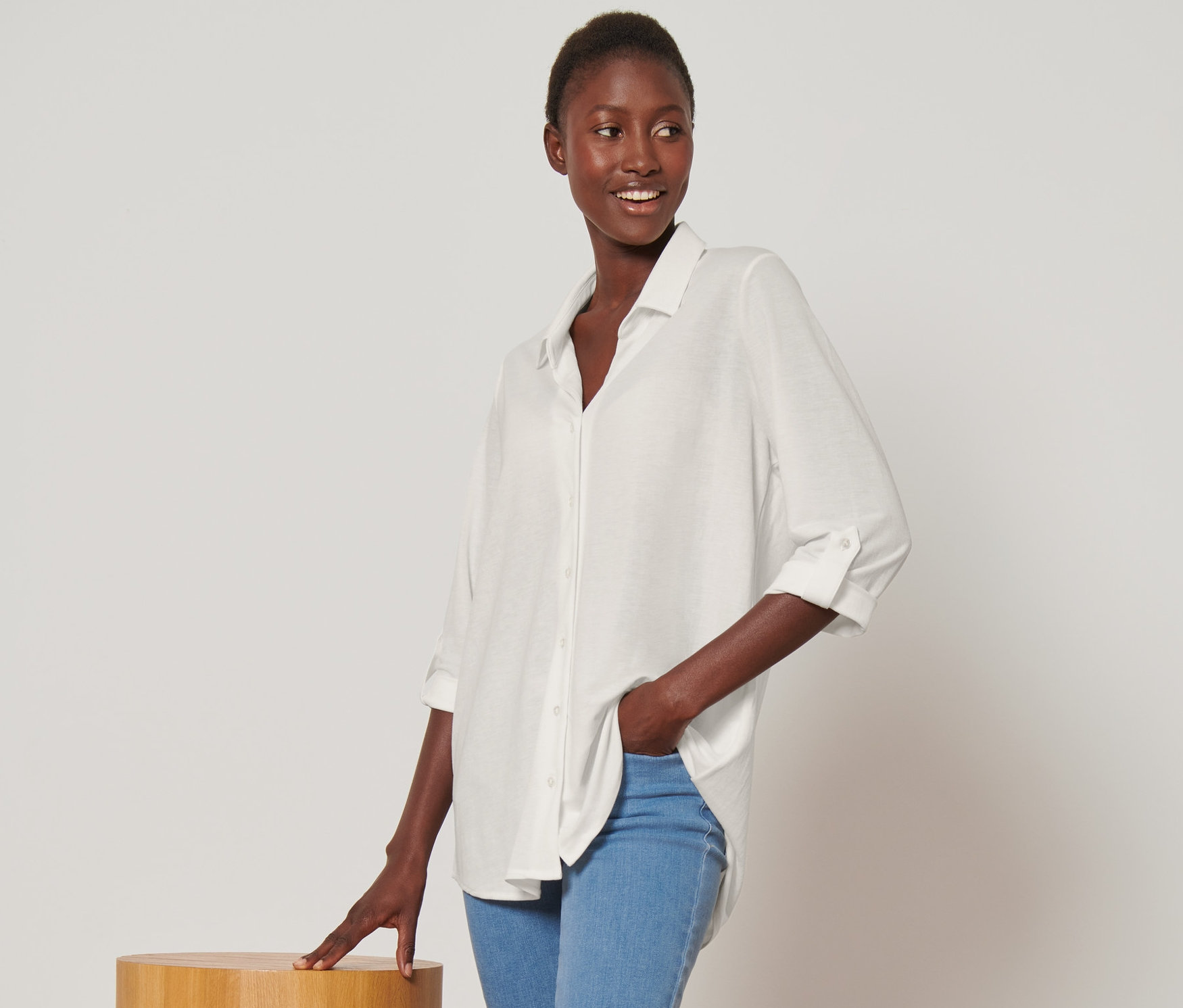 Frau posiert in cremeweißer Piqué-Jerseybluse und blauen Jeans.