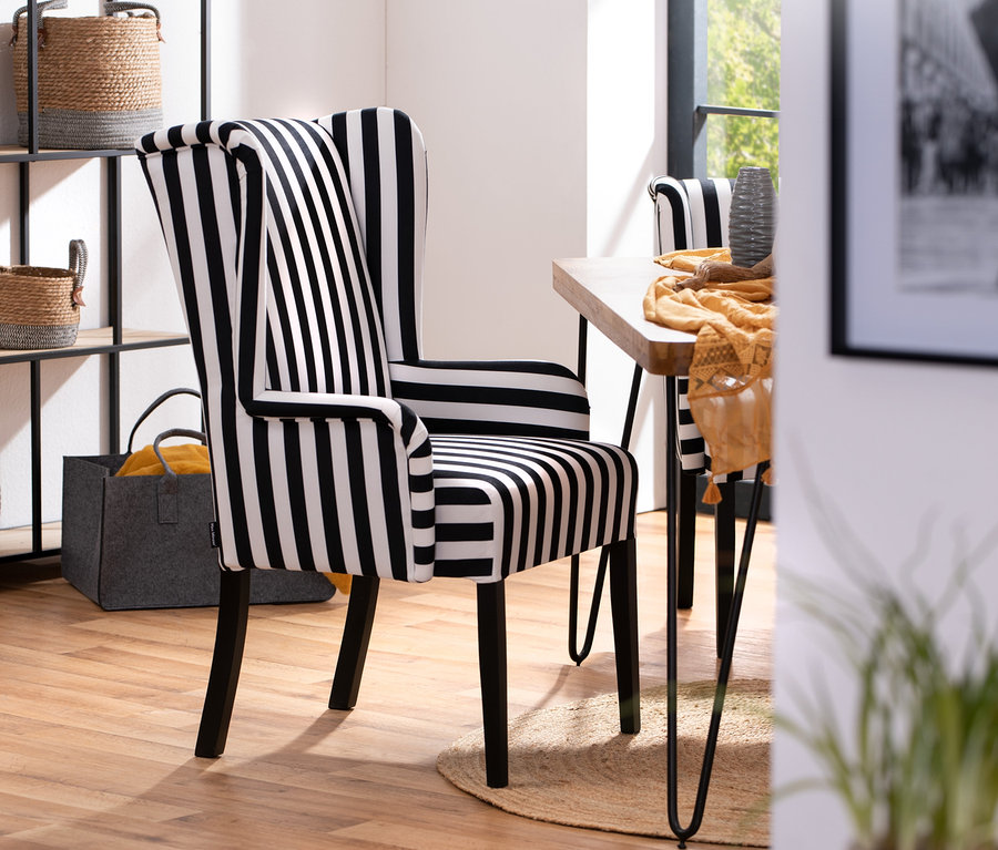 Schwarz-weiß gestreifter Hochlehner-Polsterstuhl mit Armlehne »Hendrick« steht neben einem Tisch.