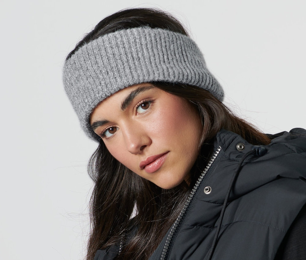 Frau trägt ein Strick-Stirnband und eine schwarze Weste.