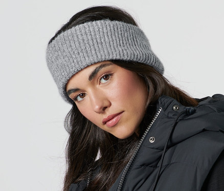 Frau trägt ein Strick-Stirnband und eine schwarze Weste.