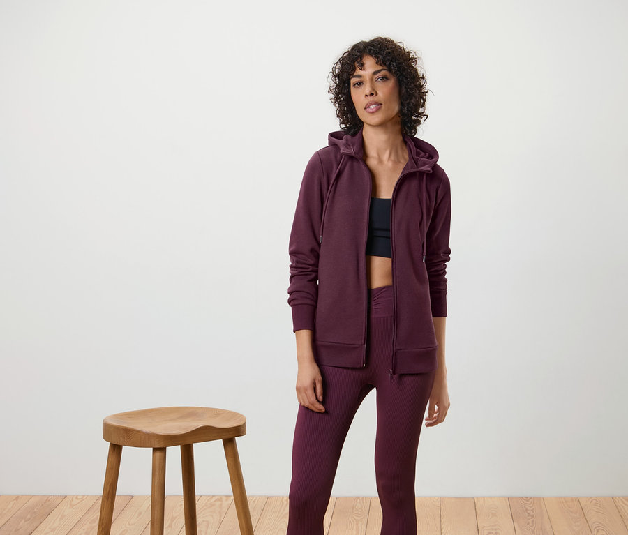 Frau trägt eine Sweatjacke, Leggings und ein Sporttop.