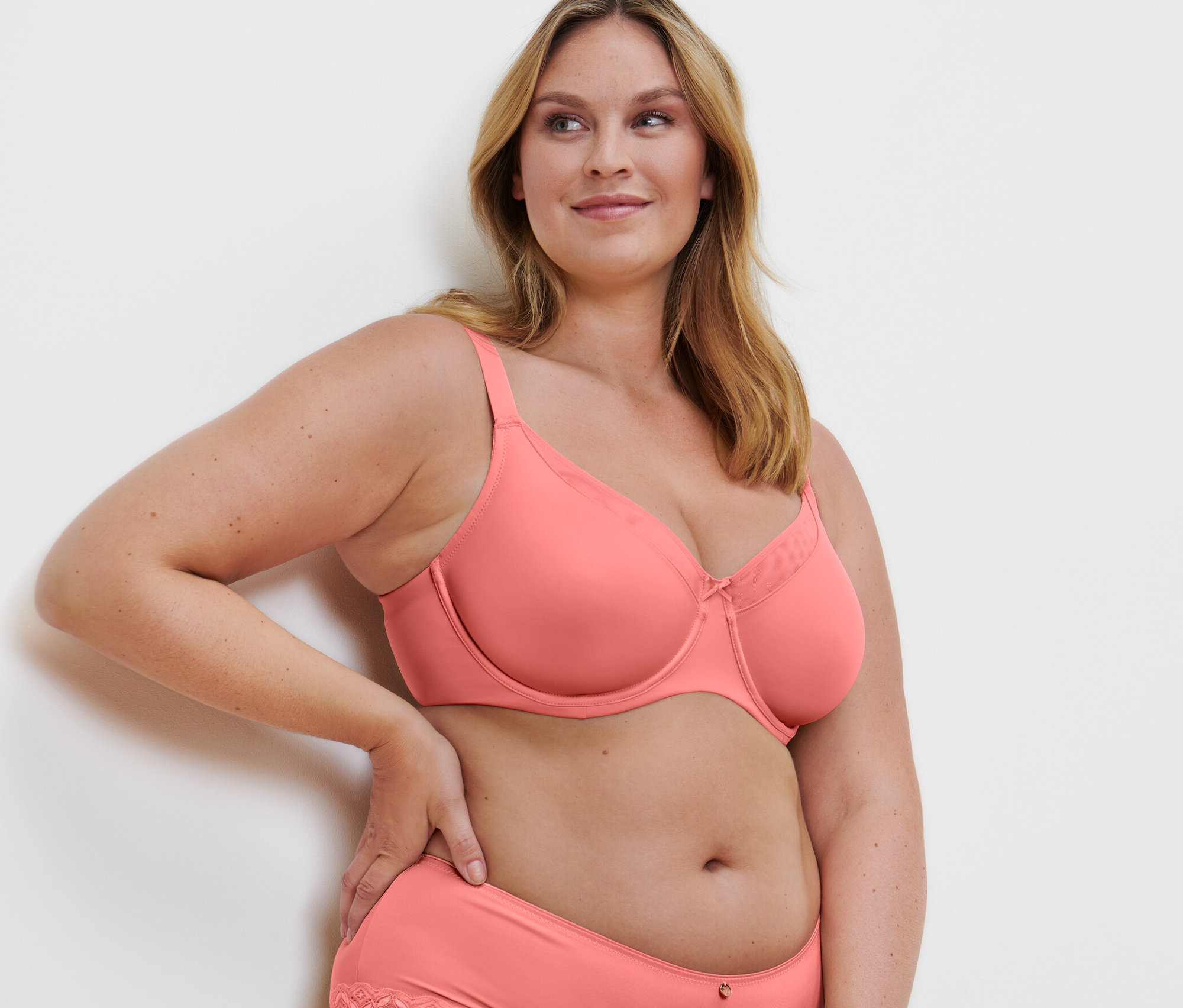 Blonde Frau posiert in Minimizer-BH und Slip mit Spitze, Papaya.