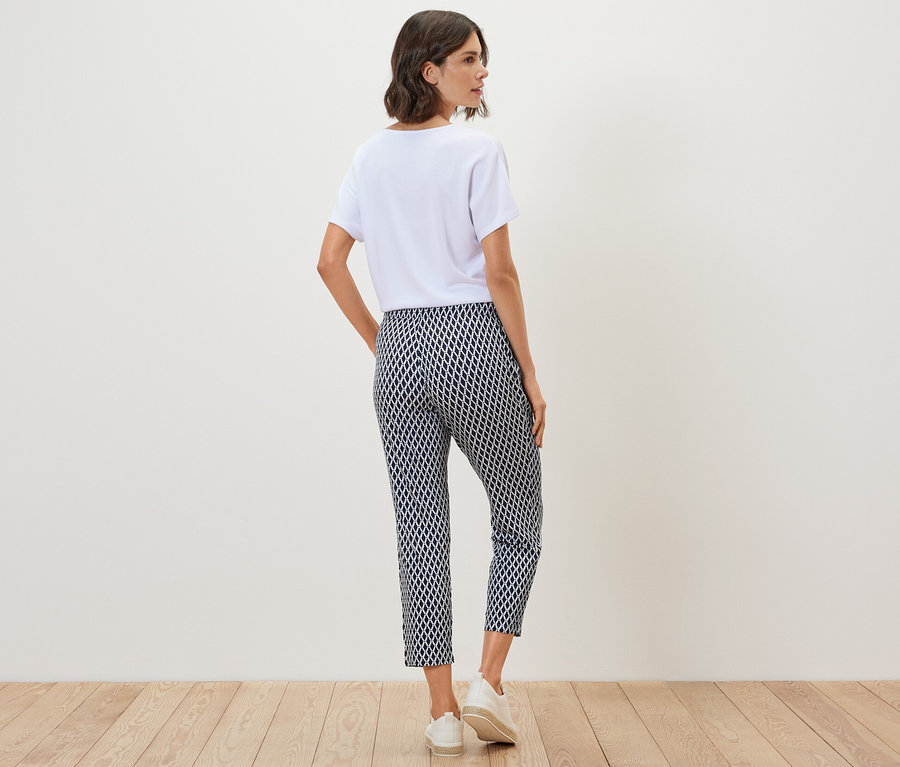 Frau von hinten in weißem T-Shirt und bedruckter Jerseyhose.