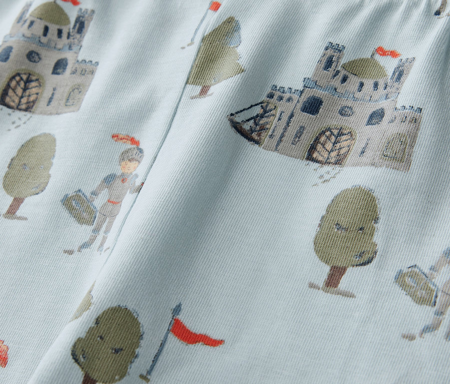 Detailaufnahme von hellblauen Kinderleggings mit Ritter-, Burg- und Baumdruck.