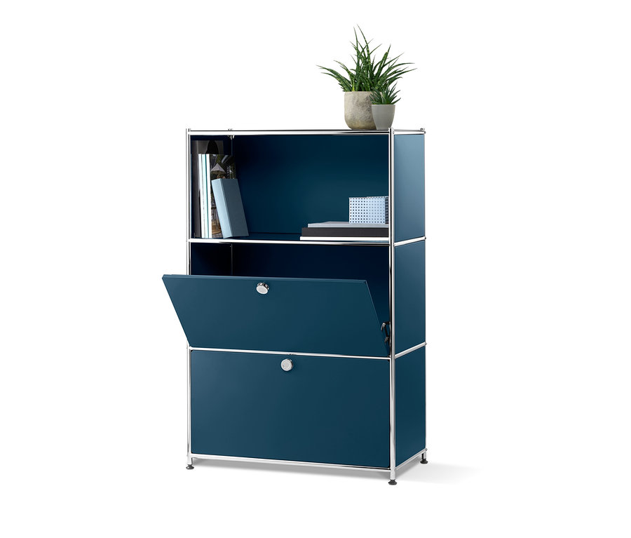 Eine blaue Kommode »CN3« mit 2 Klappen, wobei eine Klappe geöffnet ist. Oben befinden sich Bücher und eine Topfpflanze.