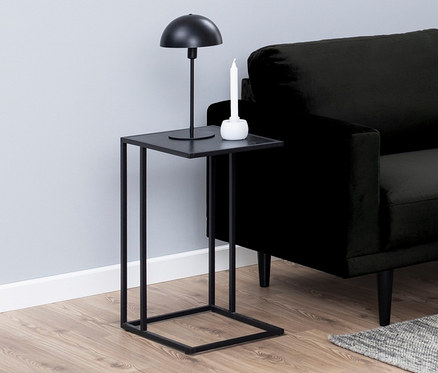Schwarzes Sofa mit beigen Kissen in einem Wohnzimmer mit einem schwarzen Beistelltisch in C-Form.