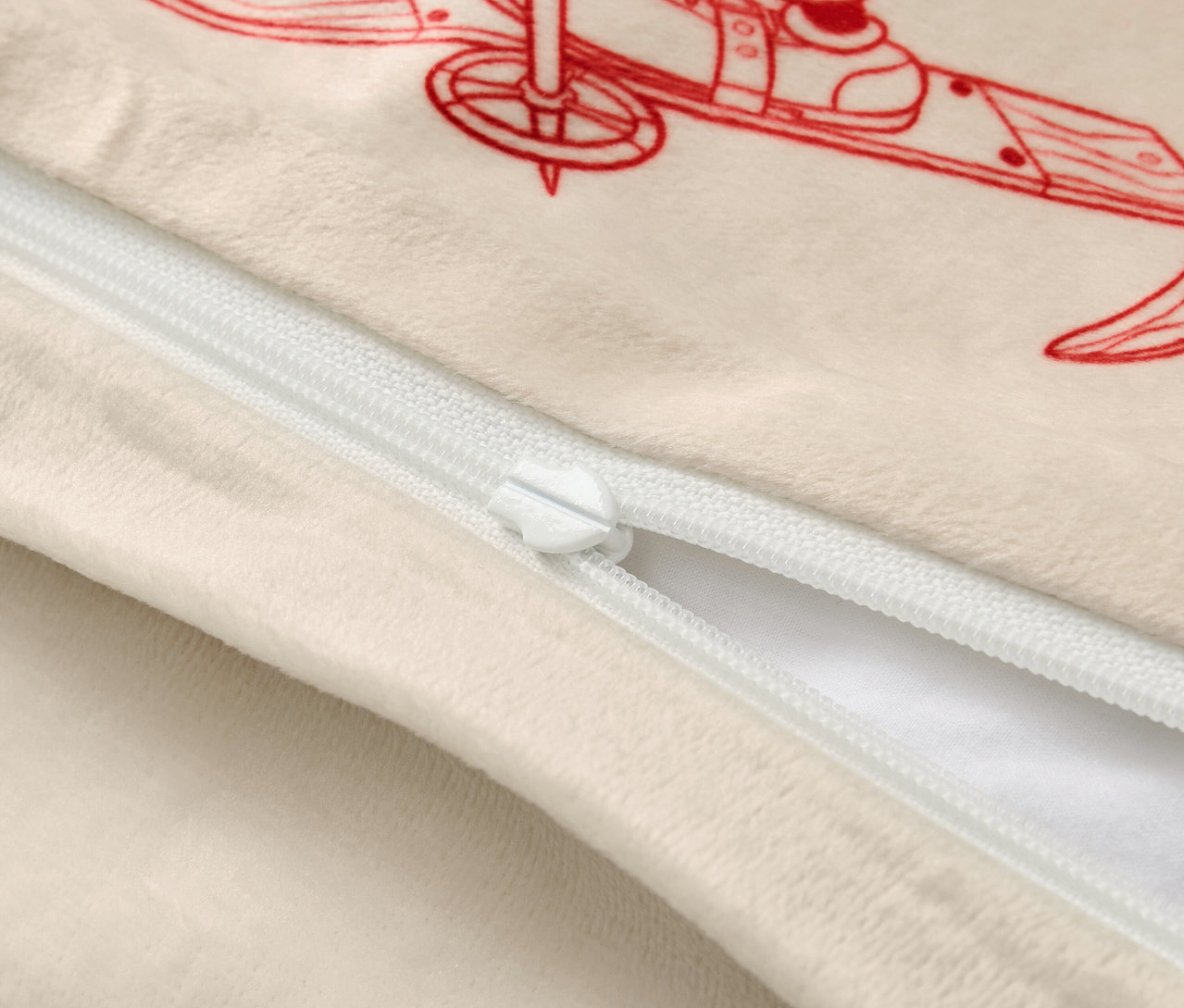 Beiger Kissenbezug mit roter Skifahrer-Illustration und weißem Reißverschluss.