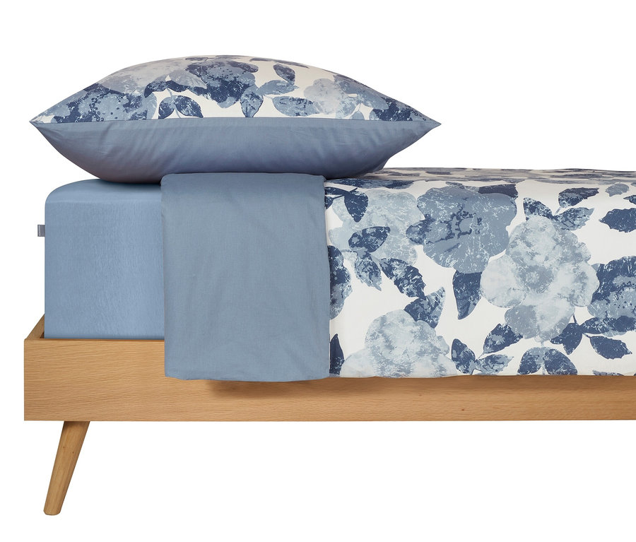 Hellblaues SCHIESSER Renforcé-Bettwäscheset »Elisa« mit Botanik-Print auf einem Bett.