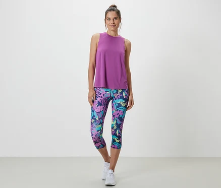 Frau trägt ein türkises Sport-Top aus einem zweiteiligen Set und Leggings mit Blumenmuster.