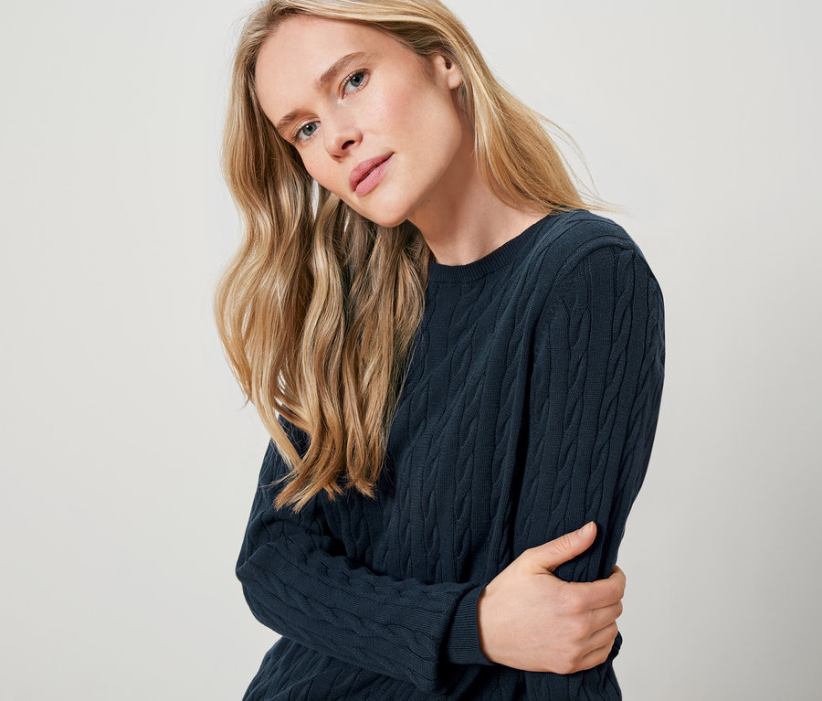 Blonde Frau trägt einen dunkelblauen Strickpullover.