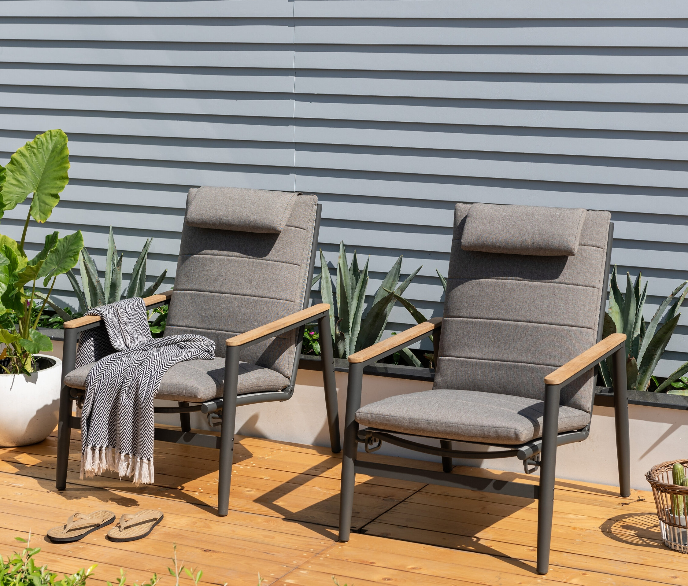 Zwei anthrazitfarbene ScanCom Outdoor-Loungesessel mit verstellbarer Rückenlehne stehen auf einer Holzterrasse.
