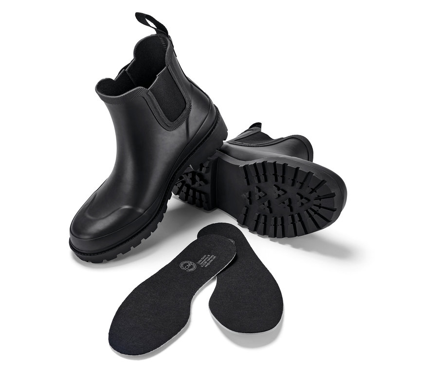 Zwei schwarze Stiefel und zwei schwarze Einlegesohlen auf weißem Hintergrund.