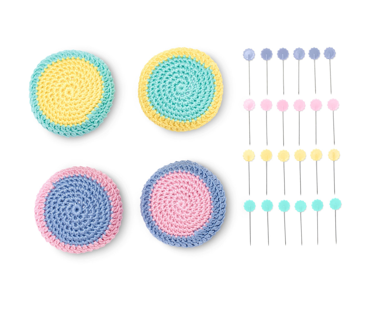 Vier Nähgewichte, zwei gelb-türkis, zwei blau-rosa. Daneben liegen Stecknadeln mit farbigen Köpfen.