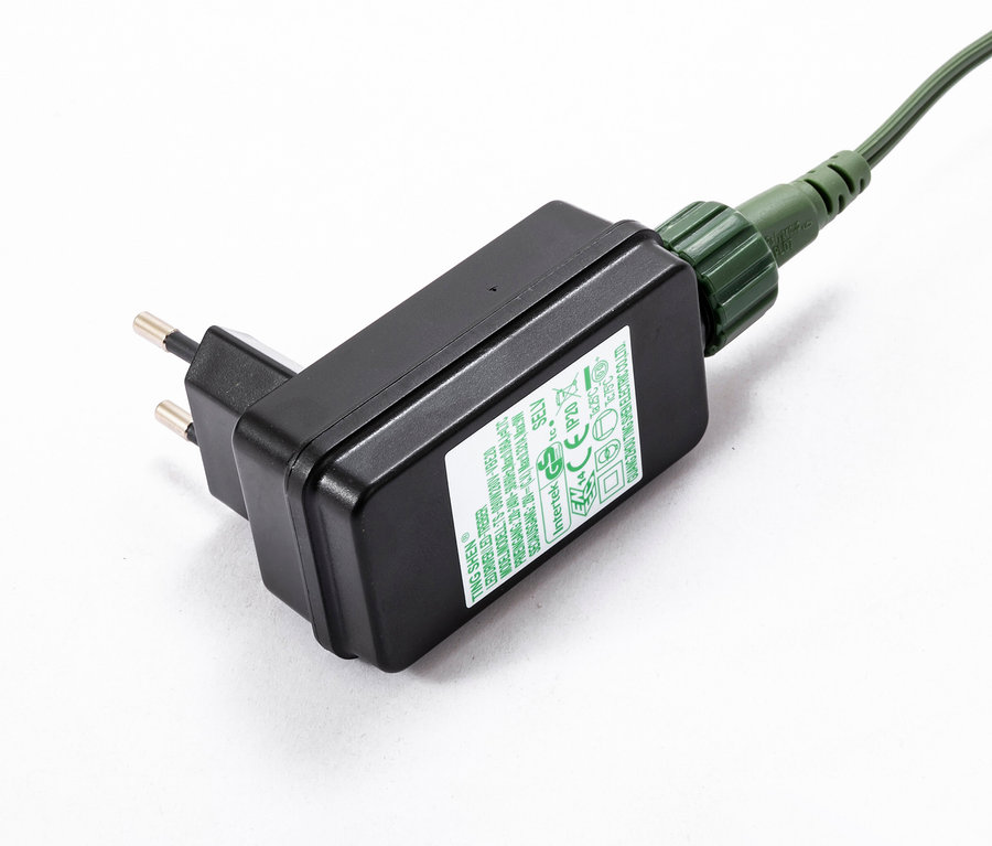 Schwarzes Netzteil mit grünem Kabel auf weißem Hintergrund.
