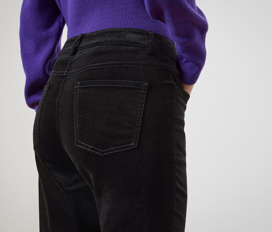 Von hinten ist eine Frau in schwarzen Jeans und einem lila Pullover zu sehen.