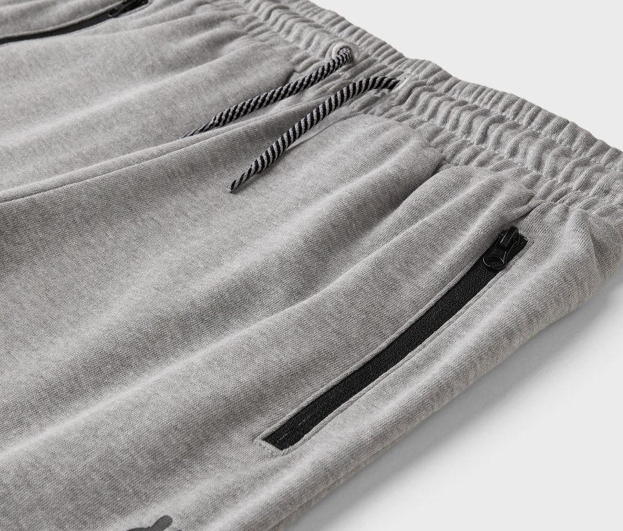 Detailaufnahme einer grauen Jogginghose mit Kordelzug und Reißverschlusstasche.
