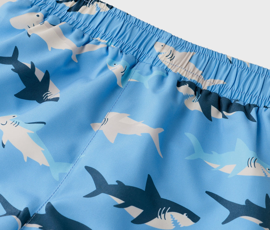 Nahaufnahme einer Badehose mit hellblauem Hai-Muster und elastischem Bund.