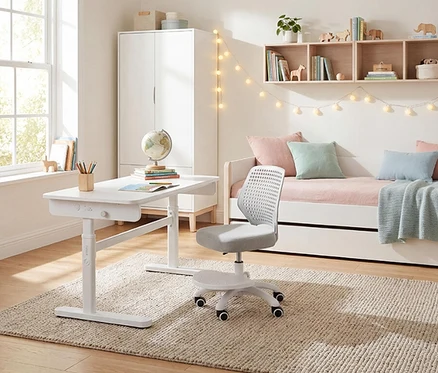 Ein Kinderzimmer mit weißem Schreibtisch, Stuhl, Bett mit Kissen und Regalen mit Dekorationen.