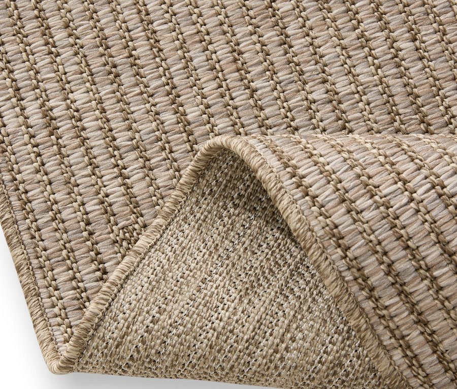 Nahaufnahme eines beigen Teppichs mit gefalteter Ecke, die die Textur zeigt.