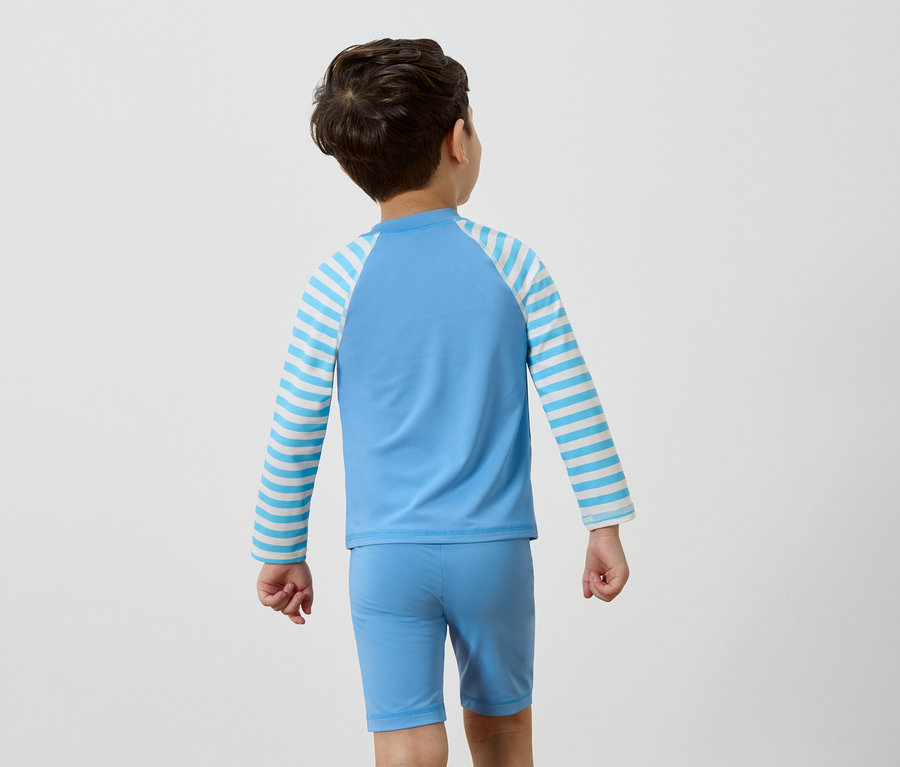Rückansicht eines Jungen, der ein hellblaues Badeoberteil mit blau-weiß gestreiften Ärmeln und eine passende Badehose trägt.