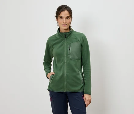 Frau mit einer grünen Fleecejacke mit Reißverschluss und blauen Hosen.