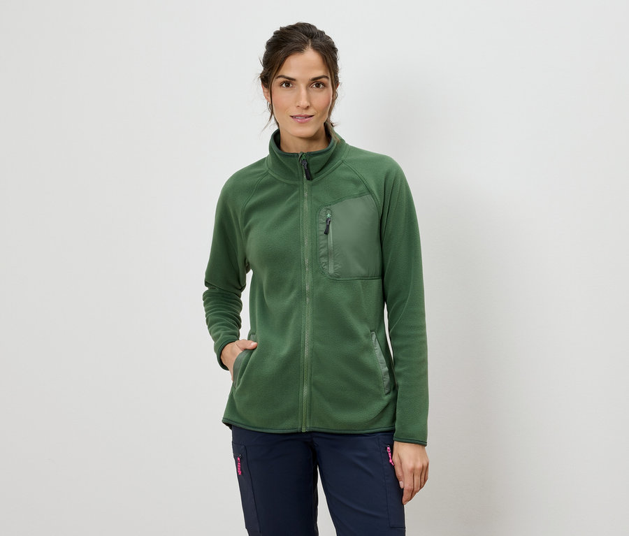 Frau mit einer grünen Fleecejacke mit Reißverschluss und blauen Hosen.