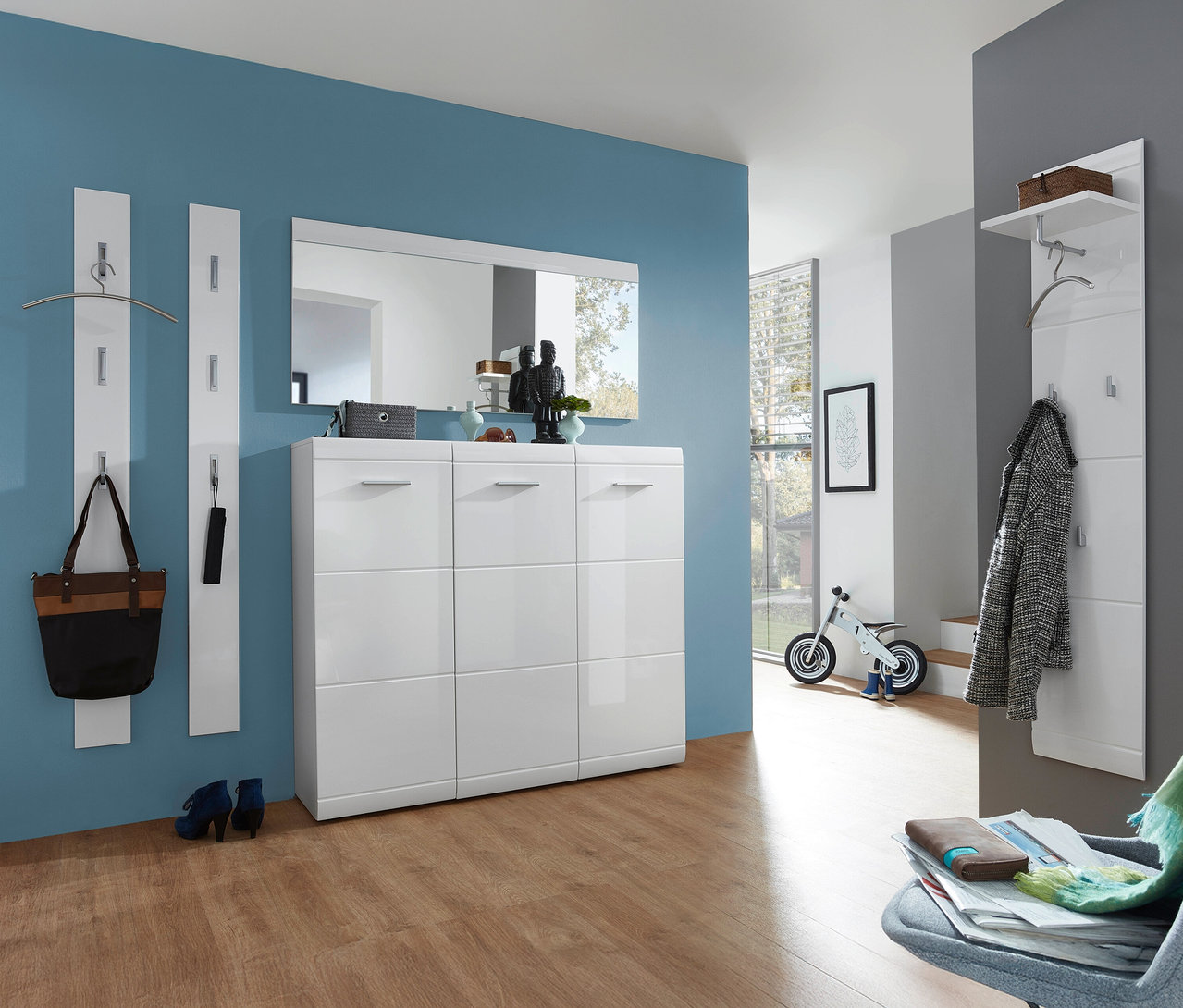 Flur mit blau gestrichener Wand, Schuhschrank »ADANA« mit drei Türen, Spiegel und Garderobenpaneelen.