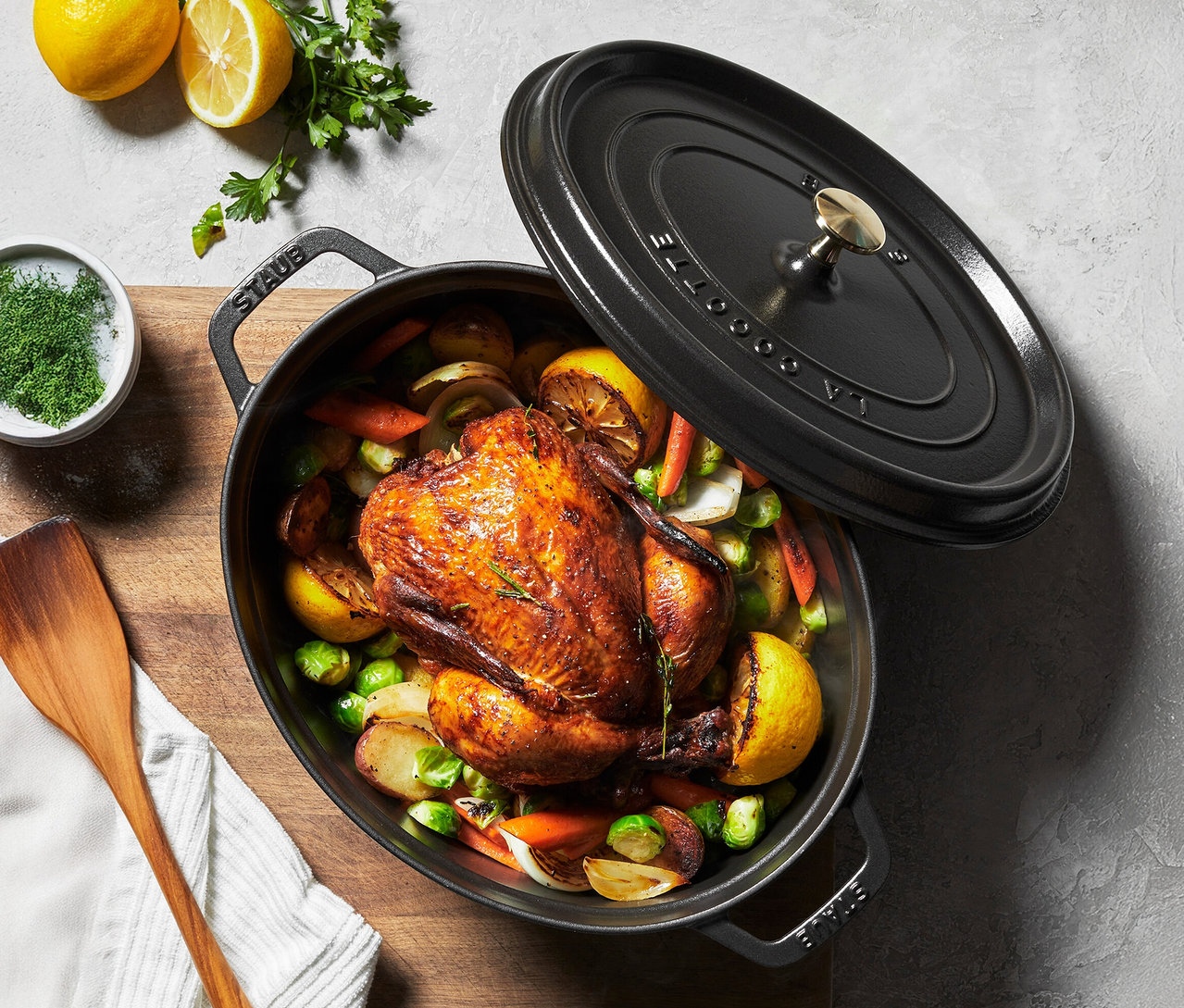 Ein Brathähnchen mit Gemüse und Zitrone in einem schwarzen STAUB Bräter »Cocotte 33« (ca. 6,7 l).