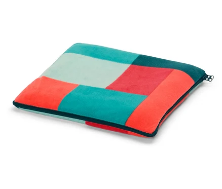 Ein quadratisches Kissen mit einem geometrischen Muster aus türkisen, roten und hellblauen Quadraten liegt auf einem weißen Hintergrund.