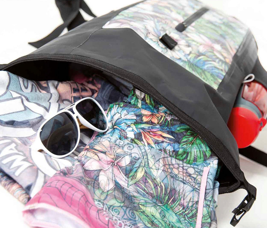 Geöffneter, gemusterter Rucksack mit Kleidung, Sonnenbrille und Trinkflasche.