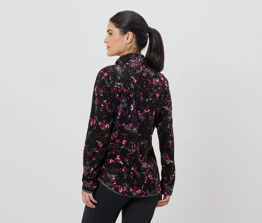 Frau von hinten in gemusterter Fleecejacke mit Reißverschluss und schwarzen Leggings.