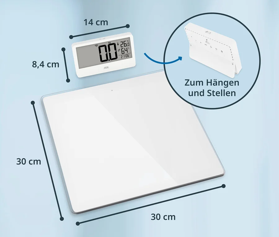 Eine weiße digitale Personenwaage, 30x30 cm, mit einem kleineren weißen Display, 14x8,4 cm. Das Display zeigt 0,0 kg, 26,0 °C, 64 % Luftfeuchtigkeit und 21:06 Uhr. Das Display kann aufgehängt oder aufgestellt werden.