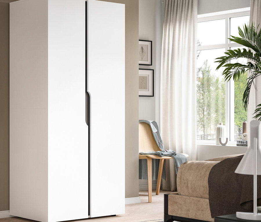 Weißer zweitüriger Kleiderschrank mit schwarzen Griffen in einem Raum mit Fenster, weißen Vorhängen, Holzstuhl, Bett und gestreiftem Teppich.