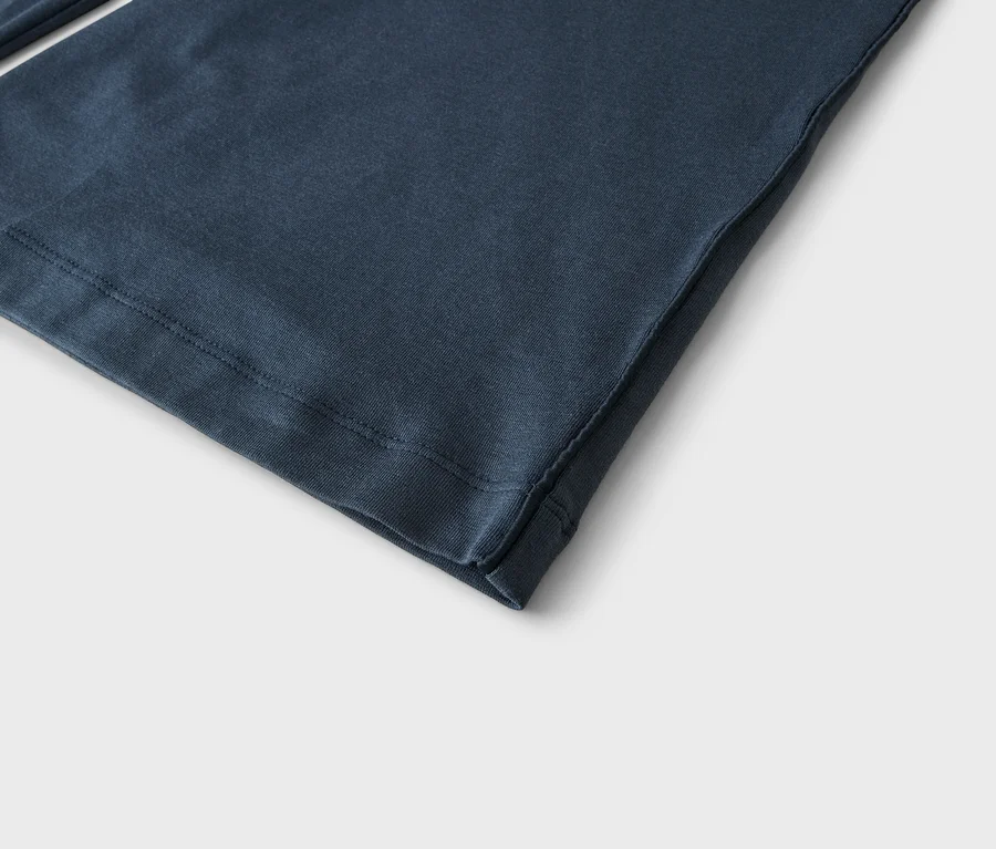 Nahaufnahme eines dunkelblauen Stoffes, der den Saum mit sichtbaren Nähten und eine Seitennaht zeigt.