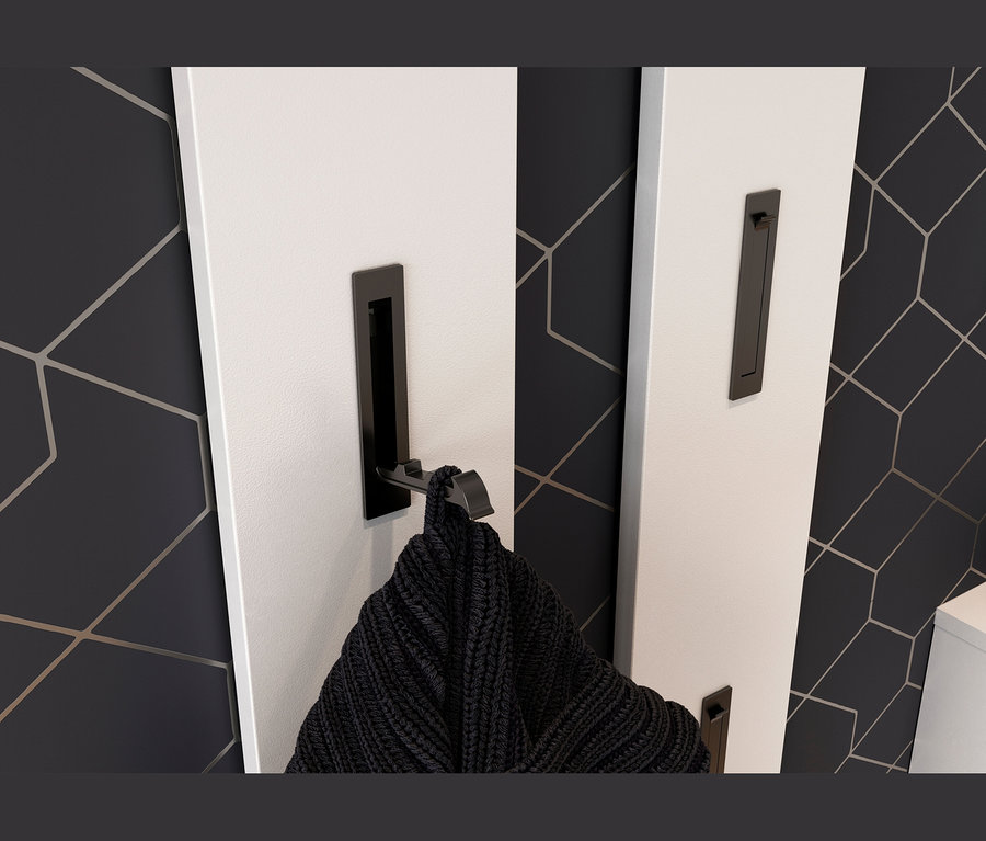 Weißes Garderobenpaneel mit schwarzen Haken, an einem hängt ein schwarzes Strickteil. Dunkle Wand mit geometrischem Muster.
