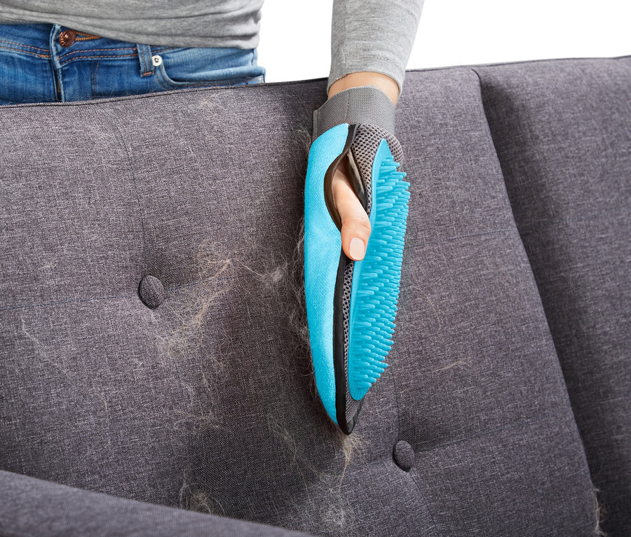 Frau entfernt Haare von Sofa mit Fellpflege-Handschuh.