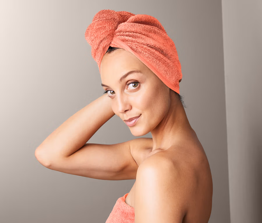 Frau mit Turban-Handtuch auf dem Kopf und einem Handtuch um den Körper gewickelt.