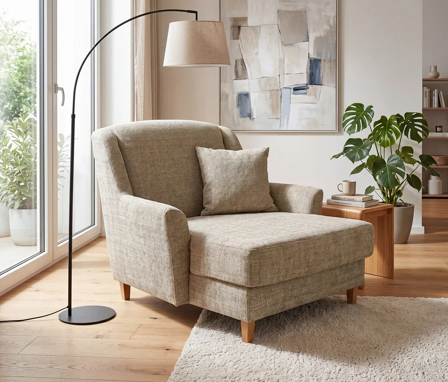Beiger Polstersessel mit Kissen neben einer schwarzen Bogenlampe mit Stoffschirm. Ein Holztischchen mit Tasse und Büchern steht neben einer großen Grünpflanze. An der Wand hängt ein abstraktes Bild, ein heller Langflorteppich liegt auf dem Holzboden.
