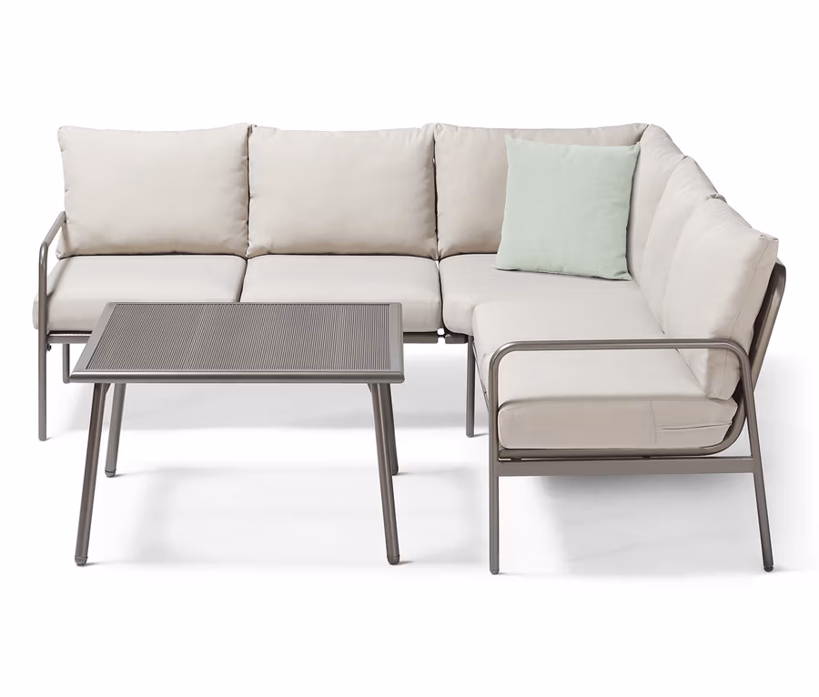 Ein Garten-Dining-Lounge-Set, Ecke, mit beigen Polstern und einem Tisch mit Metallrahmen.
