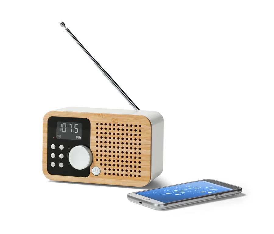 Ein FM-Kompaktradio »Bambus« mit ausgefahrener Antenne steht neben einem Smartphone.