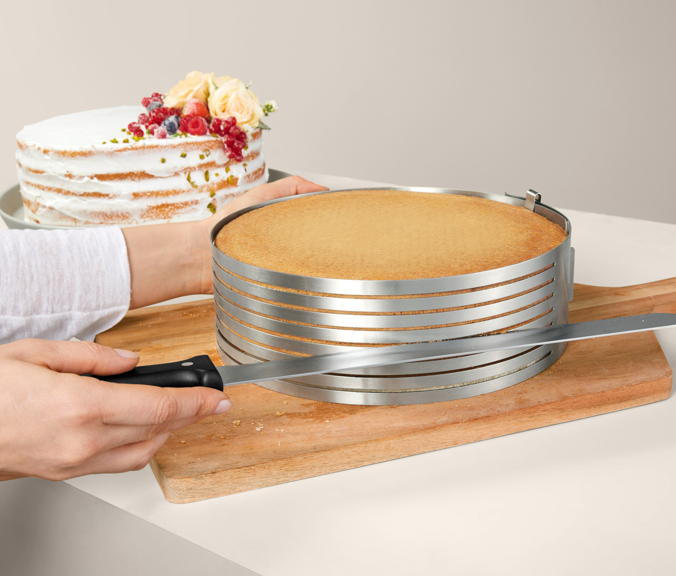 Person schneidet Tortenboden mit Tortenbodenschneidhilfe mit Konditor- und Glasurmesser.