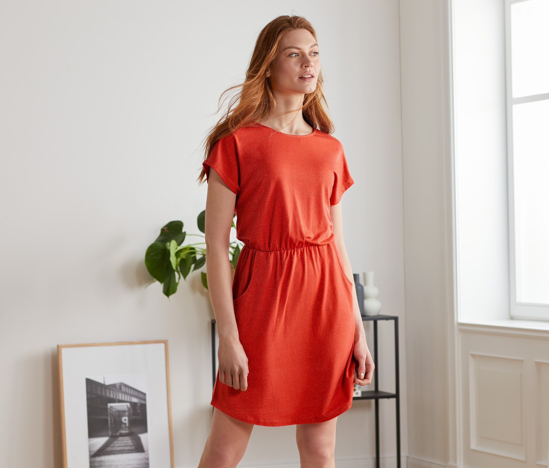 Frau posiert drinnen in einem roten Jerseykleid.