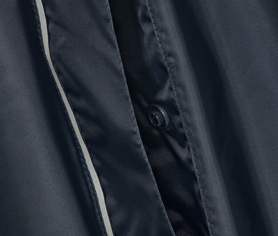 Detailansicht eines blauen Regenponchos mit Knopf und Reflektorstreifen.