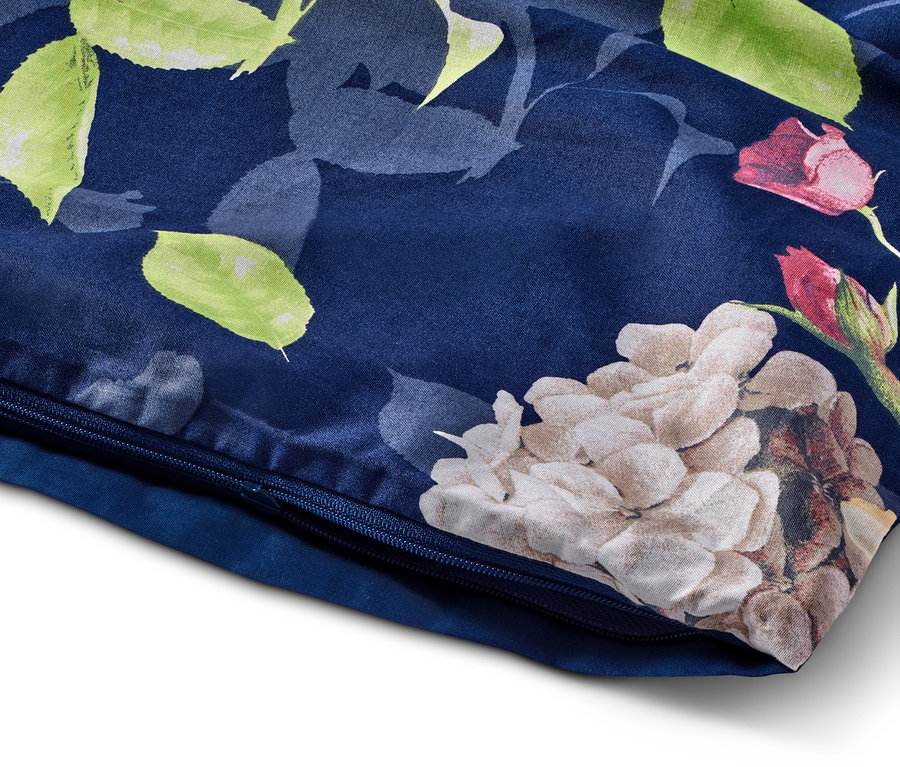 Detail eines blauen Kissenbezugs mit Blumenmuster und Reißverschluss.