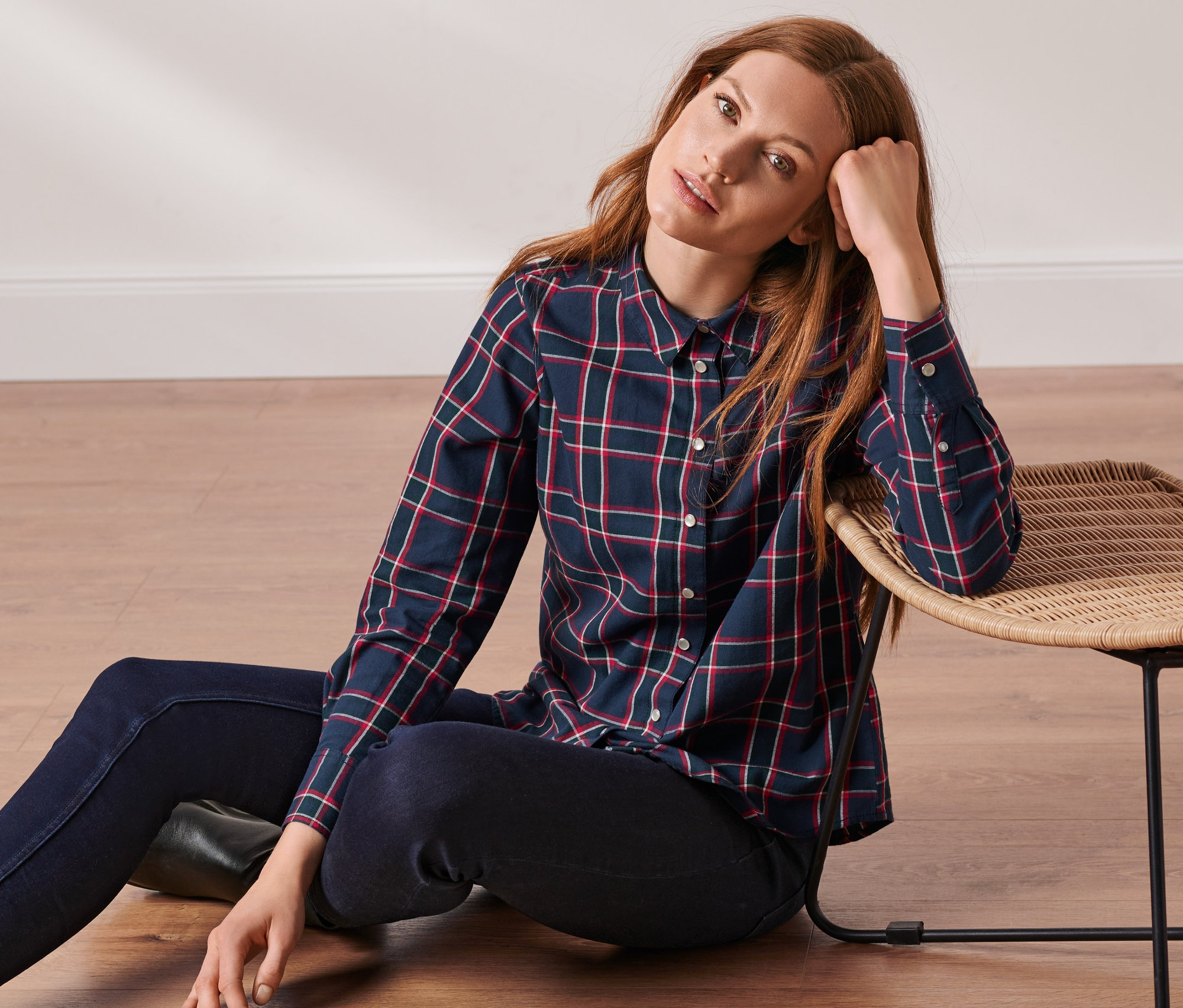 Frau sitzt auf dem Boden und trägt eine karierte Bluse aus Baumwoll-Flanell.