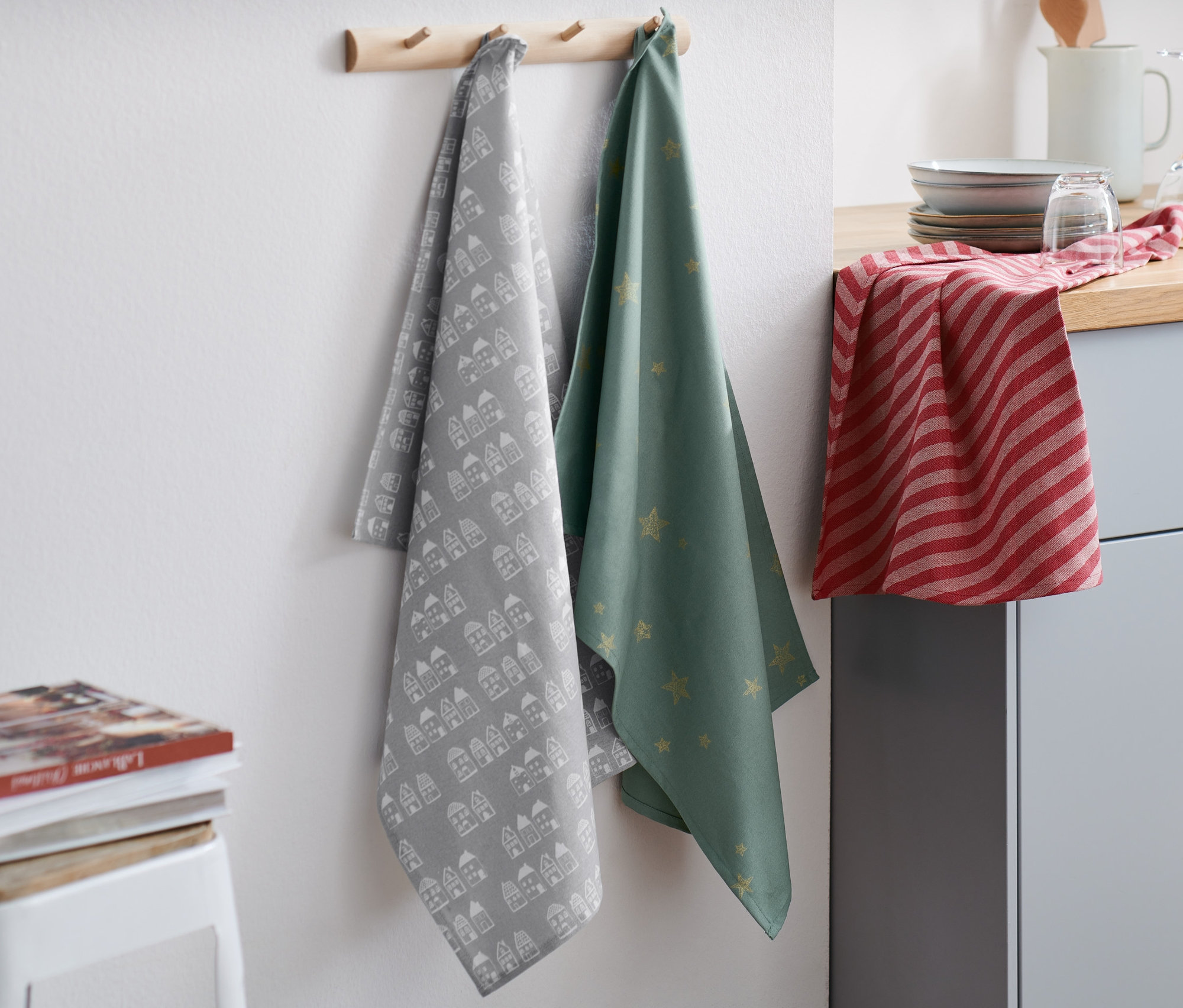 Drei Geschirrtücher hängen an einer Holzleiste.