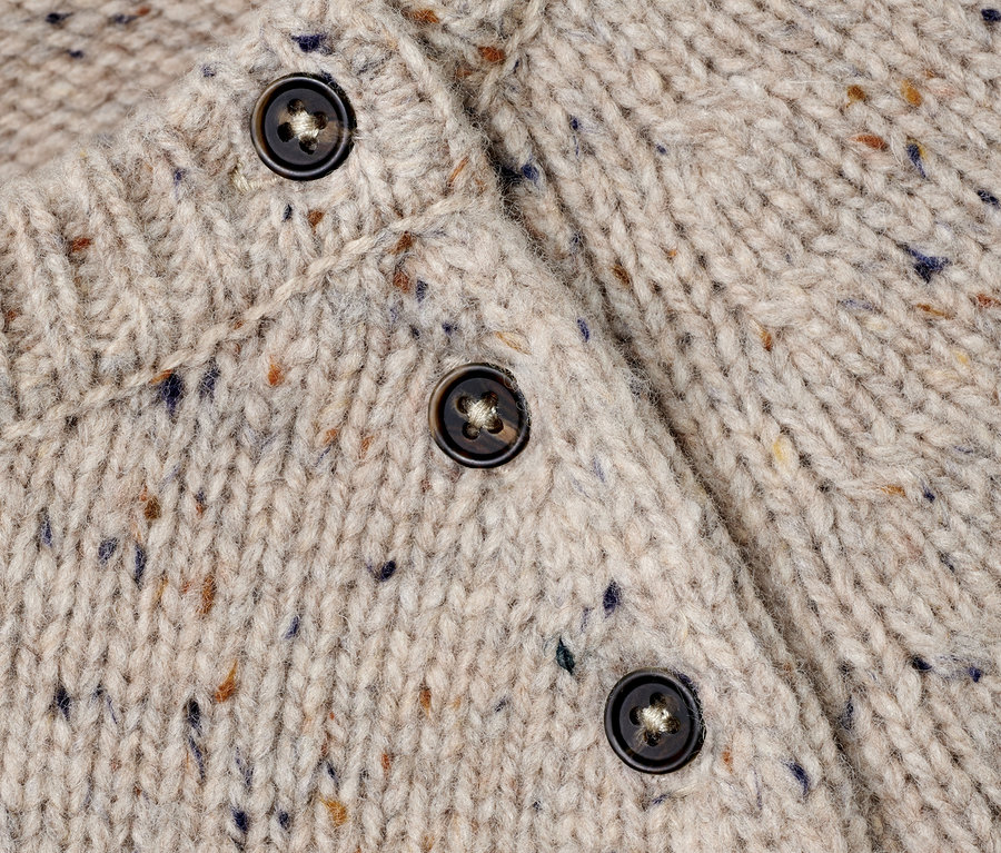 Detailansicht eines Strickpullovers mit RWS-Wolle und braunen Knöpfen.