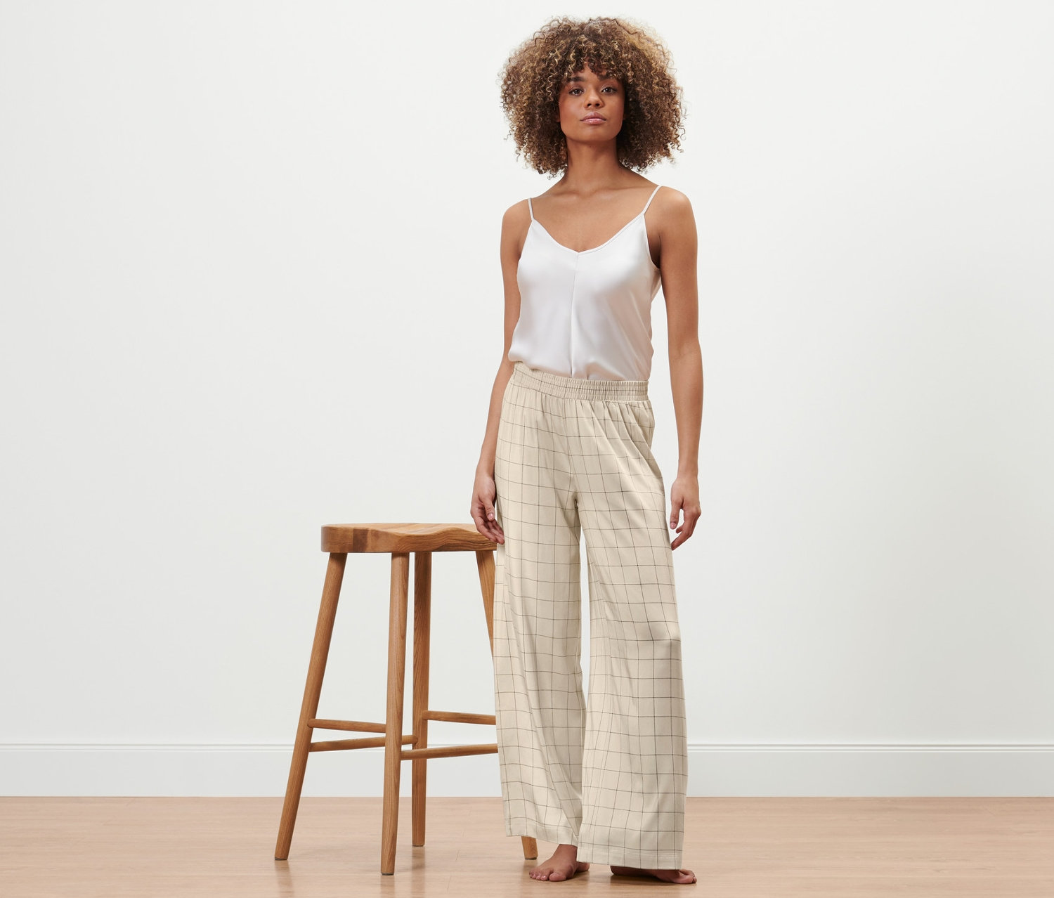 Frau steht und trägt ein weisses Top und eine Relaxhose.