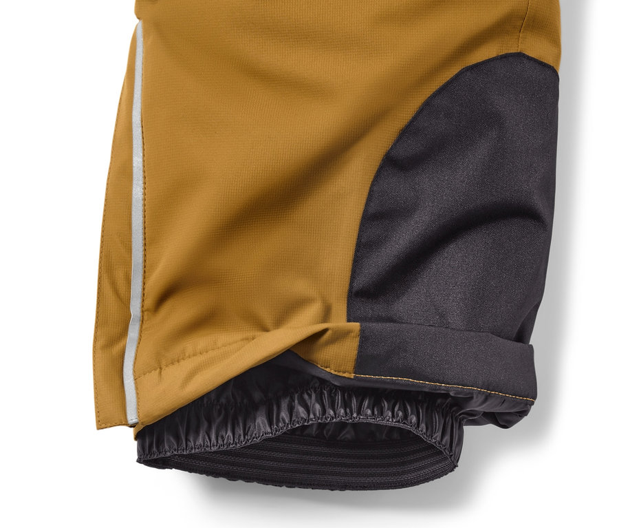 Detail einer Kinder-Skihose in Camel mit schwarzem Stoff und einem reflektierenden Streifen.