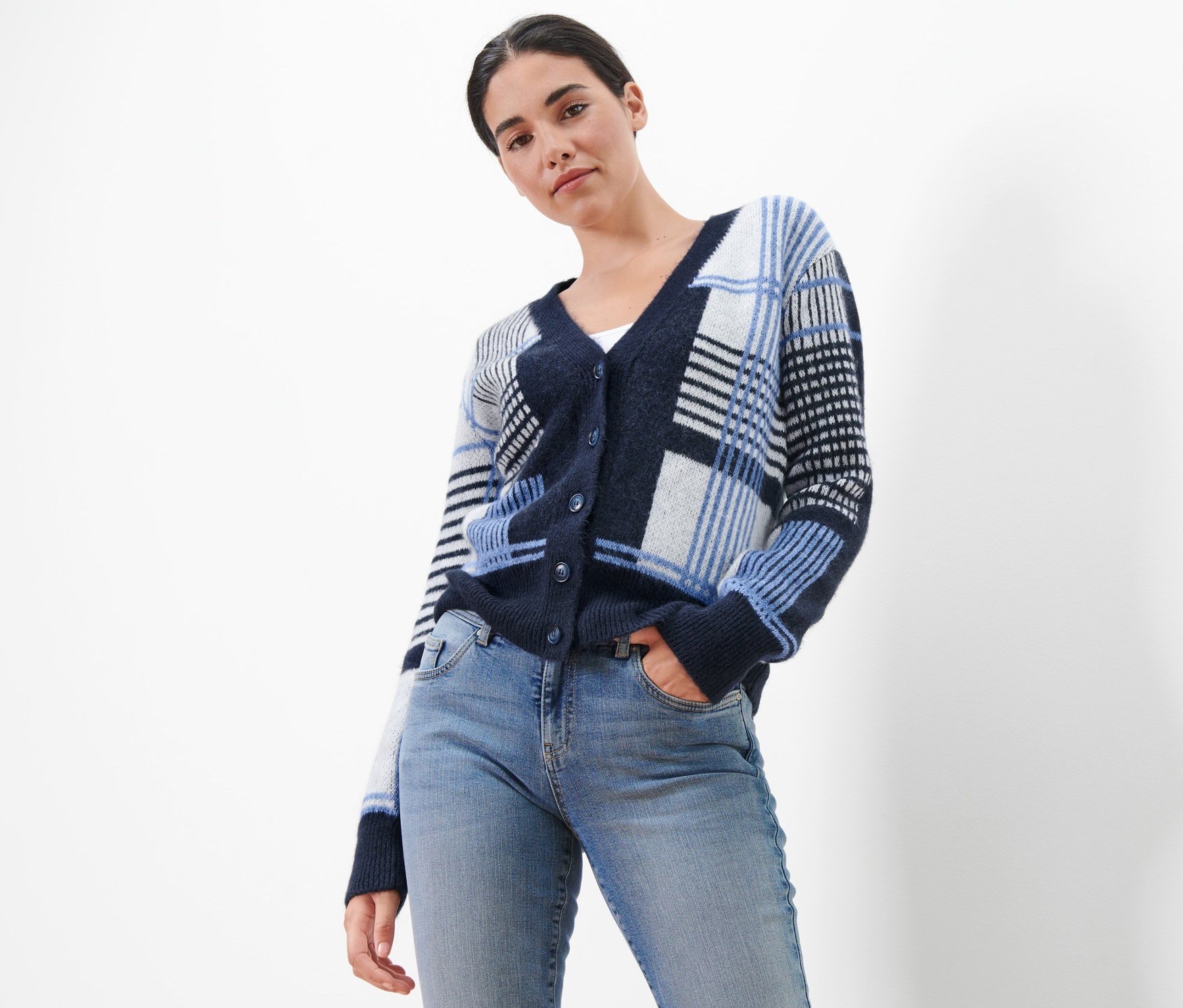 Frau posiert in Grobstrick-Cardigan und Jeans.